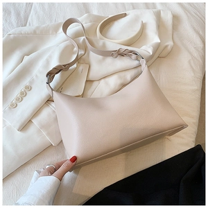 Dettaglio borsa hobo in pelle beige con tracolla intrecciata e stile minimalista chic