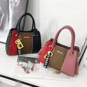 Sacs à main élégants bicolores avec pendentif B et ruban sur un bureau blanc