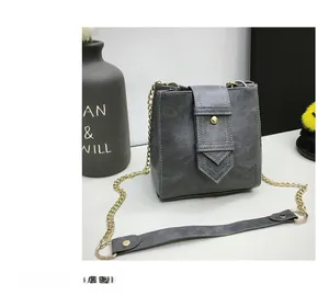 Detail view of a gray blue leather bucket bag featuring gold chain strap and metal rivets