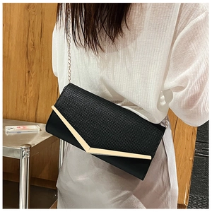 Close-up of black clutch bag with woven texture, gold V-metal trim and chain strap