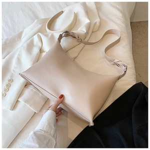 Dettaglio della borsa hobo minimalista crema con texture litchi su un blazer chic