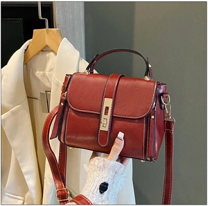 Dettaglio borsa rosso vino in pelle cerata con cuciture bianche e chiusura girevole dorata