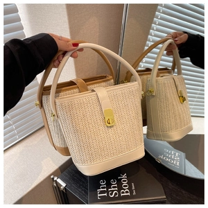 Detail view of woven bucket bags with leather handles and gold-tone twist-lock closures