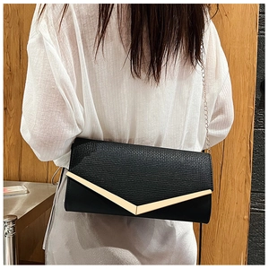 Modern black leather clutch bag with gold V-shape trim shown on model as shoulder chain bag