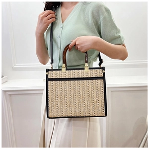 Detail of woven straw tote with tortoiseshell handles and black leather trim accents