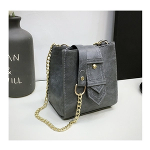 Detail of grey bucket bag with vertical stitching and golden metal chain strap