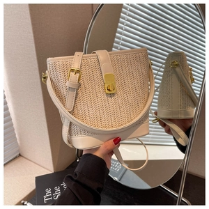 Detail view of woven bucket bag featuring gold turn-lock closure and premium leather straps