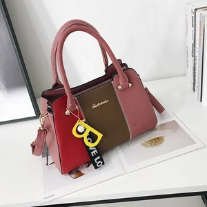 Sac à main en cuir tricolore avec panneaux roses rouges et bruns sur table blanche