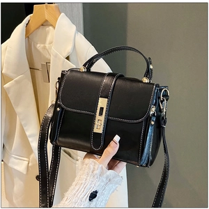 Dettaglio borsa vintage in pelle cerata con cuciture bianche a contrasto e chiusura oro