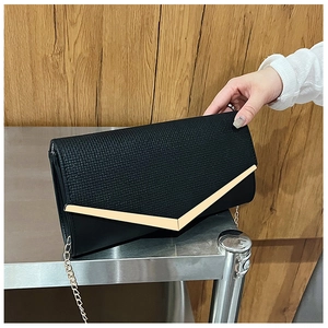 Detail of black envelope clutch featuring woven texture with V-shaped gold metal trim
