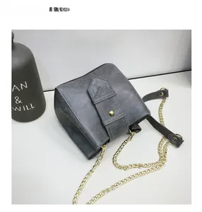 Detailed top view of a dark grey bucket bag with a golden buckle and chain strap