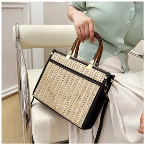 Detail of hand-woven tote bag with amber resin handles and leather stitching details