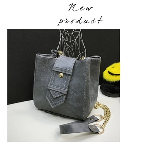 Detail of dark gray crossbody bag featuring gold studs and elegant chain strap
