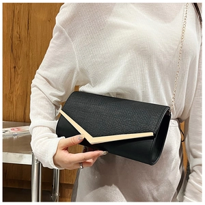 Detail of black clutch bag with dual-texture flap and gold V-shaped metal buckle detail