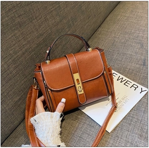 Dettaglio della borsa vintage in pelle marrone con chiusura dorata e manico superiore