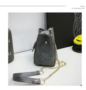 Detail of dark gray leather bucket bag featuring gold metal chain and textured finish