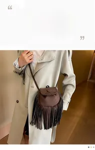 Detail of dark brown suede saddle bag featuring hand-woven stitching and long fringe tassels