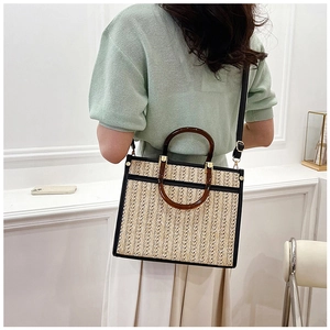 Detail showing amber resin handles and woven straw texture on minimalist tote bag