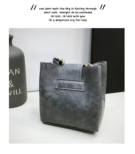 Close-up of a minimalist grey vintage washed leather bucket bag with metallic ring accents