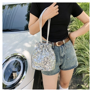 Détail du sac seau à paillettes argentées avec cordon de serrage tenu par un mannequin