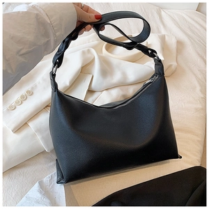 Dettaglio della borsa tote in pelle nera a grana di litchi con tracolla a treccia spessa