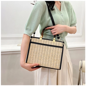 Detail of hand-woven straw tote bag with tortoiseshell handles and black leather trim