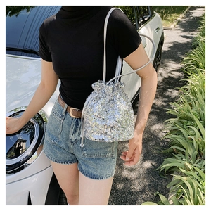 Détail d'un sac seau à paillettes argentées avec cordon de serrage porté par un mannequin