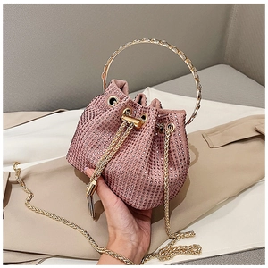 Vue détaillée du sac seau rose en strass avec poignée dorée ronde et cordon à pompons