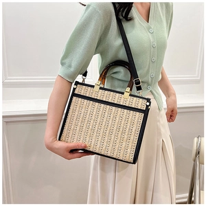Detail of woven tote bag featuring tortoiseshell handles and black leather stitching