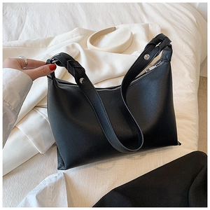 Dettaglio della borsa tote in pelle nera con tracolla intrecciata e borchie argento