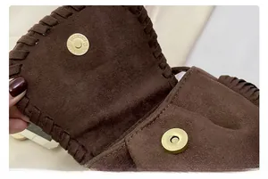 Detail of suede crossbody saddle bag showing fine stitching and gold magnetic closure