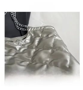 Close-up of metallic silver quilted tote with dual silver chain straps and diamond texture
