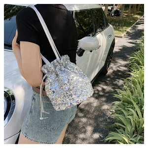 Détail du sac seau à paillettes argentées avec fermeture à cordon sous la lumière