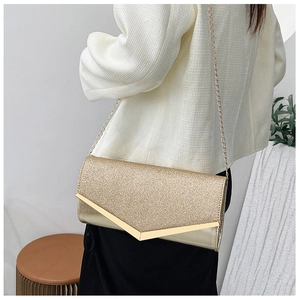 Macro detail of gold glitter evening clutch bag with V-shaped metal trim and chain strap