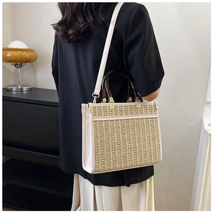Detailed side view of woven straw tote bag with amber handles and cream leather trim