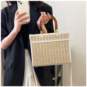 Detail of hand-woven straw tote bag with tortoiseshell handles and cream leather trim