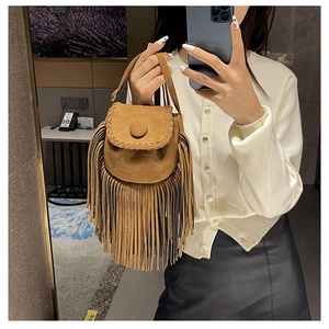 Close-up of brown suede saddle bag with long bohemian fringe worn with casual outfit