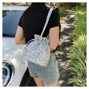 Sac seau argenté à paillettes avec cordon porté à l'épaule en lumière naturelle