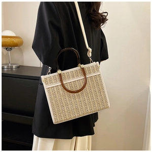 Detail of woven straw tote bag featuring white leather trim and tortoiseshell resin handles
