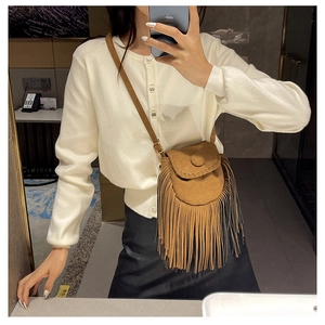 Detail of bohemian suede crossbody bag featuring long fringe and adjustable strap