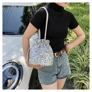 Détail du sac seau à paillettes argentées avec cordon de serrage porté par un mannequin