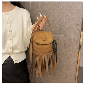 Close-up of brown suede saddle bag featuring long fringe tassels and stitching details