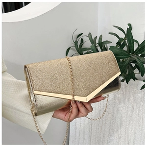 Close-up of golden luxury clutch bag featuring V-shaped metal trim and sparkly glitter texture