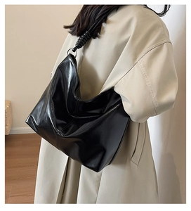 Detail of black leather hobo bag featuring knotted shoulder strap and silver ring accents