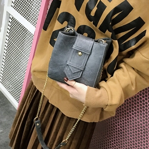 Minimalist grey cross-body phone bag with matte texture and gold chain strap on model
