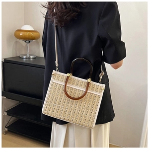 Detail of hand-woven tote bag with amber handles, white leather trim and gold hardware