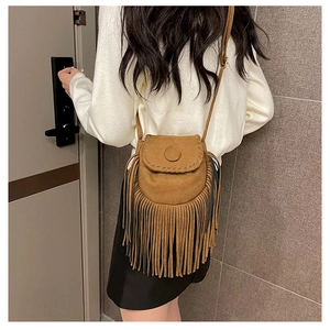 Detail of a brown suede saddle bag with long tassels and hand-stitched weaving on the flap