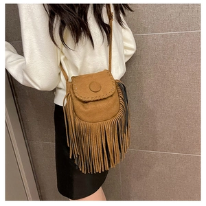 Close-up of brown suede saddle bag featuring bohemian fringe and whipstitch details