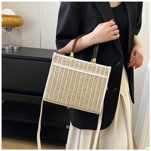 Detail of hand-woven straw tote bag with faux leather trim and tortoiseshell handles