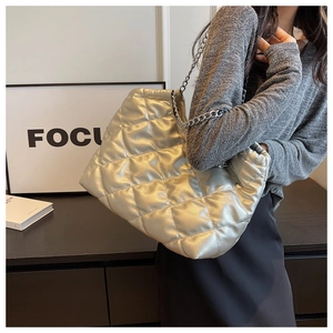 Silver quilted tote bag with diamond pattern and metal chain strap shown on a model
